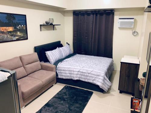 a small bedroom with a bed and a couch at Casa de Guapo - AYALA Serin East Taal View Condo in Tagaytay