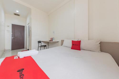 um quarto com uma cama branca com um cobertor vermelho em RedDoorz @ Malabar Street em Bandung