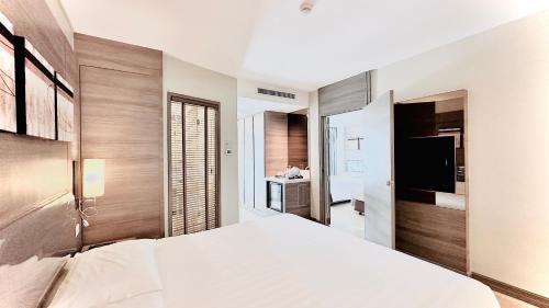 Citrus Sukhumvit 11 by Compass Hospitality في بانكوك: غرفة نوم بسرير كبير وتلفزيون