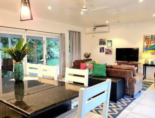 uma sala de estar com uma mesa e cadeiras e um sofá em Luxury Beachside Home em Maninoa
