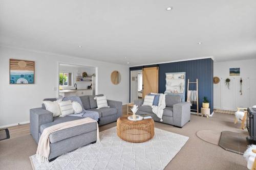 a living room with two couches and a table at Salty Air Cottage in Bream Creek