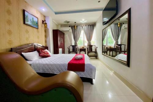 um quarto com uma cama, um espelho e uma cadeira em Hotel Phương Nam em Ho Chi Minh