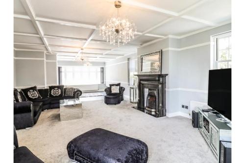 a living room with a fireplace and a chandelier at 6BD Vacation Home with Indoor Pool in Canvey Island