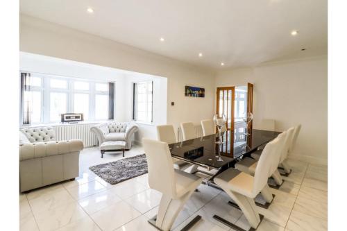 a dining room with a glass table and white chairs at 6BD Vacation Home with Indoor Pool in Canvey Island
