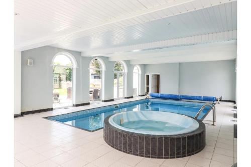 a large swimming pool with a large tub in a room at Luxurious 6 Bedroom Villa with Pool Sleeps 12 in Canvey Island