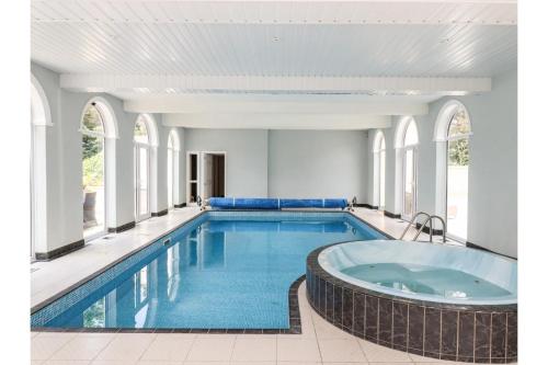 a swimming pool with a hot tub in a building at Luxurious 6 Bedroom Villa with Pool Sleeps 12 in Canvey Island