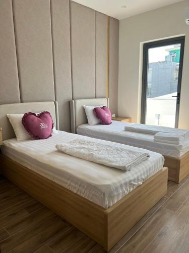 two beds in a room with pink pillows on them at Residence Á CHÂU in Vung Tau
