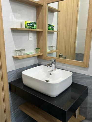 a bathroom with a white sink and a mirror at Residence Á CHÂU in Vung Tau