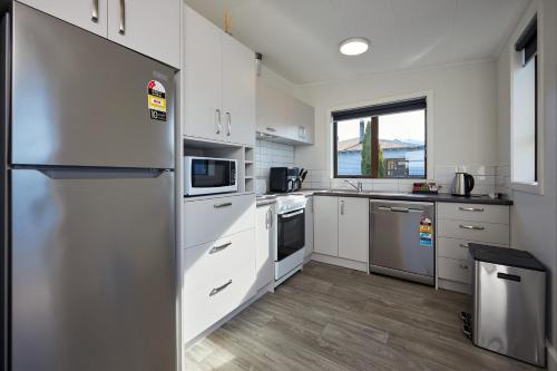 a kitchen with white cabinets and a stainless steel refrigerator at Central | Beach Nearby | Parking - KK27622 in Kaikoura