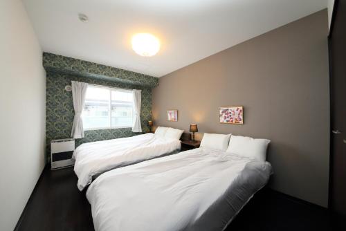 sypialnia z 2 łóżkami i oknem w obiekcie サンコート４０２ w mieście Kita-sanjō