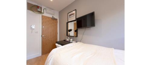 a bedroom with a bed and a flat screen tv on the wall at Cozy-Bnbs Tiny and Perfect Studio Apartment in London