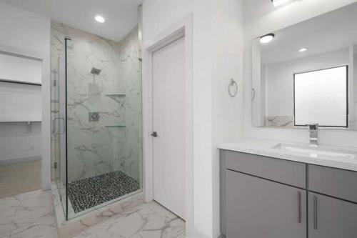a white bathroom with a shower and a sink at Houston Heights Villa in Houston