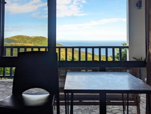 a table and chair on a balcony with a view of the ocean at Ponderosa Golf and Resort in Puerto Galera