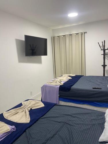 a bedroom with two beds and a flat screen tv at Golden Lake Apart Hotel Arraial do Cabo in Arraial do Cabo