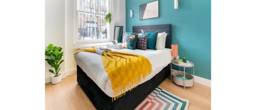 ein Schlafzimmer mit einem Bett mit einer gelben Decke darauf in der Unterkunft NEW: Bright & Stylish Perfect Studio for 2 in London