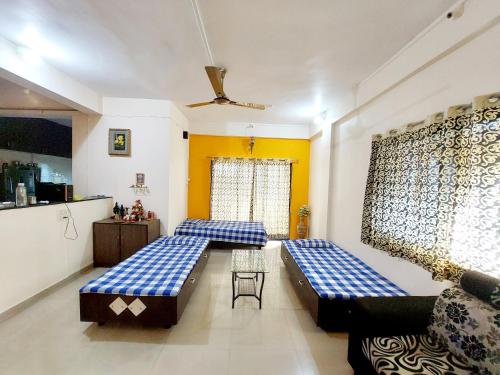 a living room with two beds and a kitchen at Muktangan Home, Kolhapur in Kolhapur