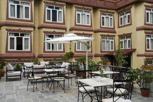 an outdoor patio with tables and chairs and an umbrella at Shambaling Boutique Hotel in Kathmandu