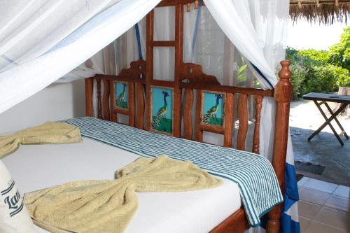 a bedroom with a wooden bed with a canopy at Driftwood Beach Lodge in Jambiani