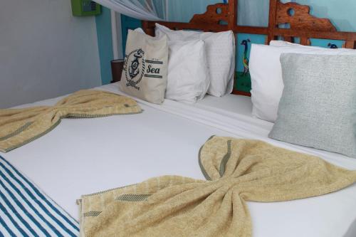 a bed with two blankets and pillows on it at Driftwood Beach Lodge in Jambiani