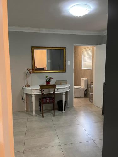a bathroom with a white desk and a mirror at Hill Luxury Cottage in Roodepoort