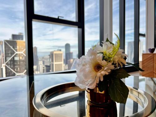 a vase with flowers on a table in front of a window at High rise top view 2bed2bath in Melbourne
