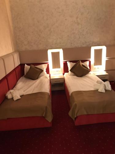 two beds in a hotel room with two lamps at Le Mer in Afumaţi