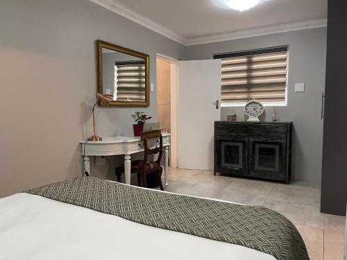 - une chambre avec un lit, un lavabo et un bureau dans l'établissement Hill Luxury Cottage, à Roodepoort