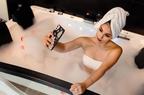 uma mulher numa banheira segurando um controle remoto em G Hotels Collect em Arequipa