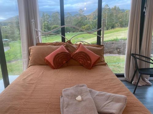 a bedroom with a bed with a large window at Nimbin waterfall retreat in Nimbin