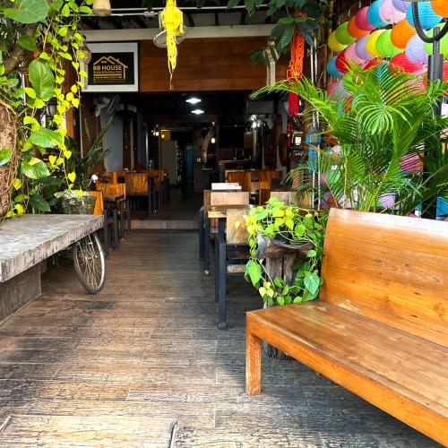 a bench in a restaurant with tables and chairs at BB House Budget & Boutique in Chiang Mai