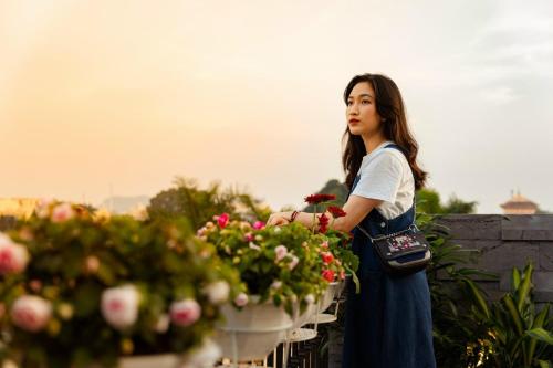 a young woman looking at flowers in a garden at Dolce Mia Home Ninh Bình in Ninh Binh