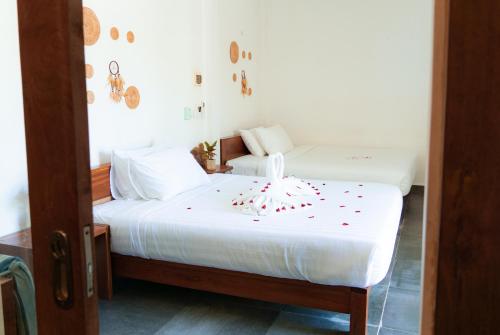 a bedroom with two beds with white sheets and red confetti at Long Set Resort in Koh Rong Island