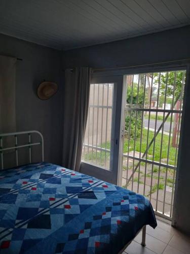 1 dormitorio con cama y ventana grande en Casa 01 dorm. 05 min da praia perfeito, en Capão da Canoa