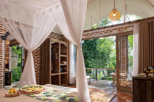 a room with a bed with a curtain over it at Sacred Canyon Ubud by GenuineHost in Payangan