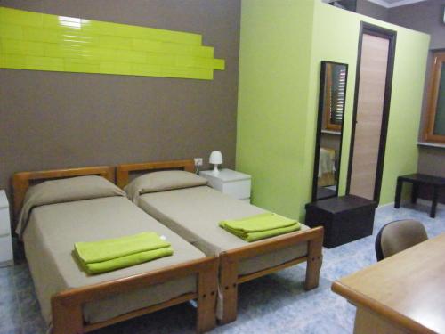 1 dormitorio con 2 camas, paredes verdes y mesa en Alborada B&B, en Salerno