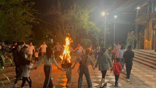 a group of people standing around a large fire at Homestay Cao Nguyên Mộc Châu in Mộc Châu