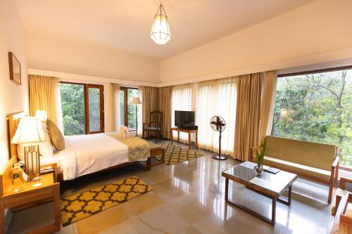 a bedroom with a bed and a living room at Saraca Resort & Spa Corbett in Garjia