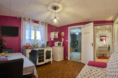 a kitchen with pink walls and a room with a table at Studio in Saint-Victor-de-Cessieu