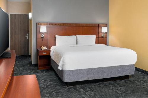 a bedroom with a large bed and a television at Courtyard by Marriott Oklahoma City Airport in Oklahoma City