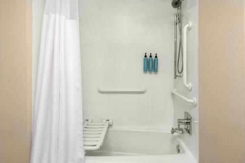 a bathroom with a shower with a white shower curtain at Courtyard by Marriott Oklahoma City Airport in Oklahoma City