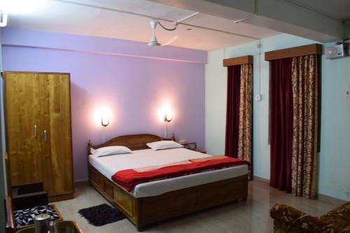 1 dormitorio con 1 cama con paredes moradas en Hotel Abhishekh, en Port Blair