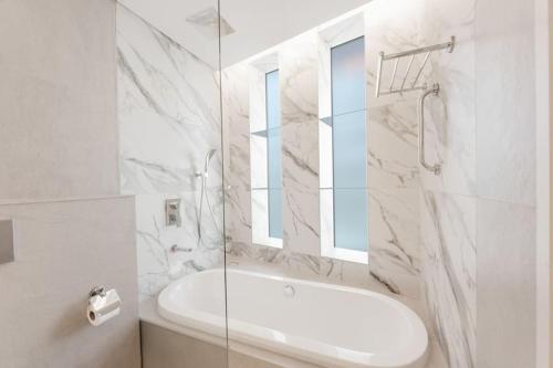 a white bathroom with a tub and a sink at Stayis - 1 BR Marina suite in Dubai