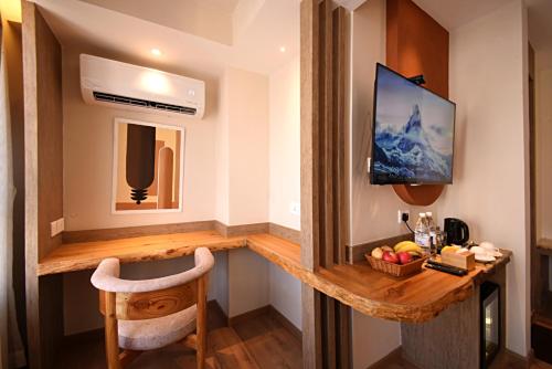 Habitación con escritorio, TV y silla. en Daali Hotel & Apartment, en Katmandú