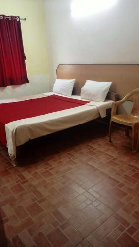 łóżko z czerwonym kocem i krzesłem w pokoju w obiekcie FLGHR Green Residency w mieście Kodaikānāl