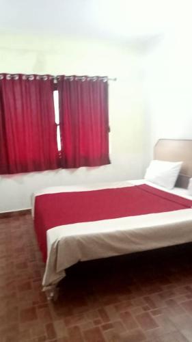 una camera da letto con un grande letto con tende rosse di FLGHR Green Residency a Kodaikānāl