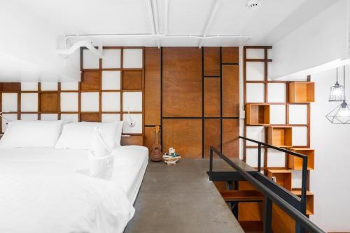a living room with white furniture and a staircase at Book a Bed Poshtel - SHA Plus in Phuket Town