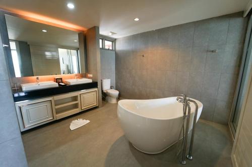een badkamer met een bad, een wastafel en een spiegel bij Serene Phla Resort and Restaurant in Rayong