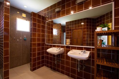 a brown tiled bathroom with two sinks and a mirror at Hacienda Resort - Mae Phim in Mae Pim