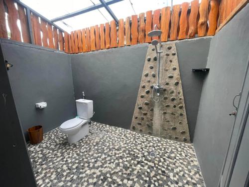 a bathroom with a shower and a toilet at SuperSuck Hotel in Maluk