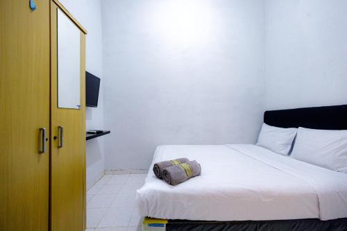 a bedroom with a white bed with a pillow on it at Marcello Residence Siwalankerto near Petra University Surabaya Mitra RedDoorz in Surabaya